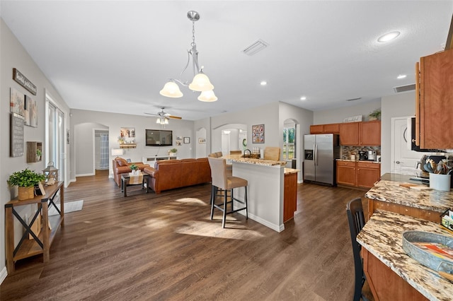 kitchen with pendant lighting, a kitchen breakfast bar, light stone countertops, and stainless steel fridge with ice dispenser