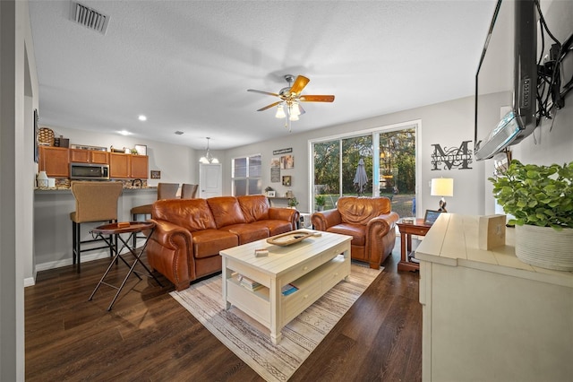 living room with wood-type flooring, ceiling fan with notable chandelier, and a textured ceiling