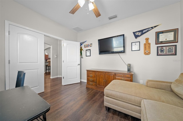 living room featuring dark wood-type flooring and ceiling fan