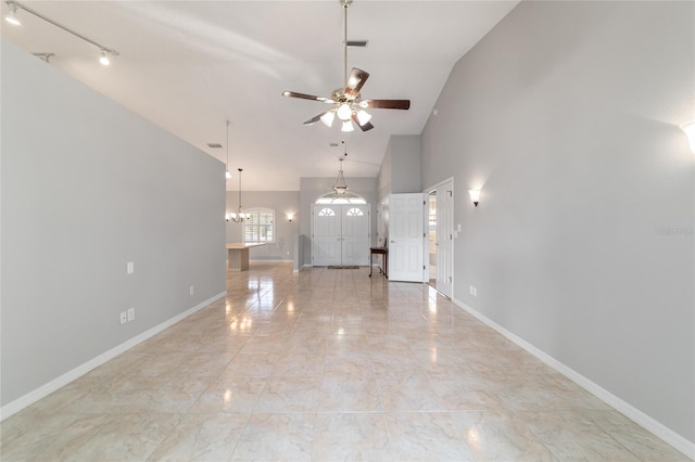 unfurnished living room featuring ceiling fan with notable chandelier, track lighting, and high vaulted ceiling