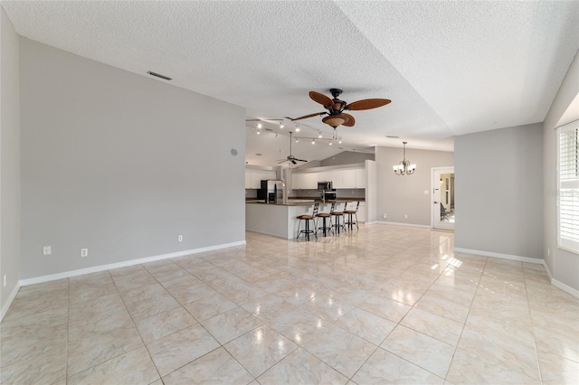 unfurnished living room featuring ceiling fan with notable chandelier, vaulted ceiling, and a textured ceiling