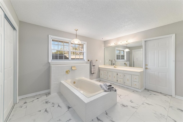 bathroom with vanity, tiled bath, and a textured ceiling