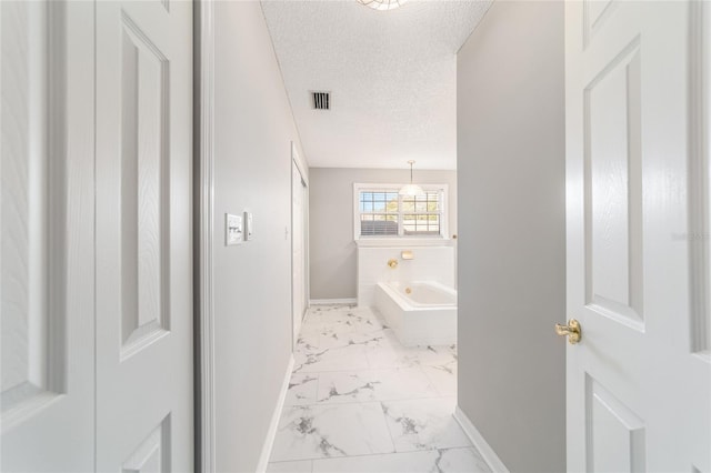 bathroom featuring tiled bath and a textured ceiling