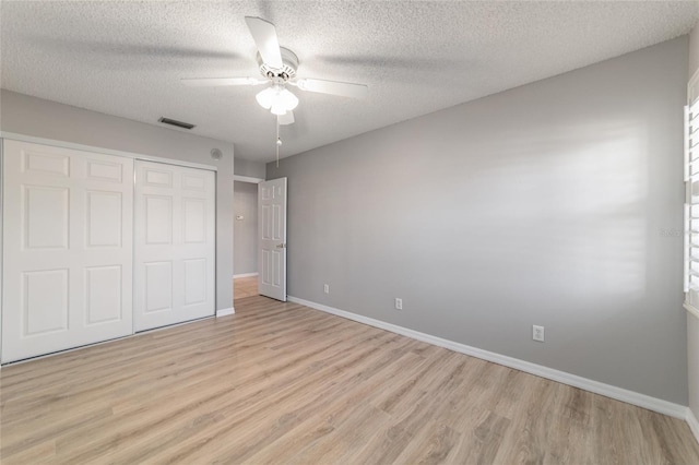 unfurnished bedroom with ceiling fan, light hardwood / wood-style flooring, a closet, and a textured ceiling