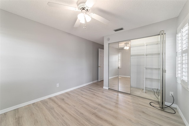 unfurnished bedroom featuring ceiling fan, a textured ceiling, light hardwood / wood-style floors, and a closet