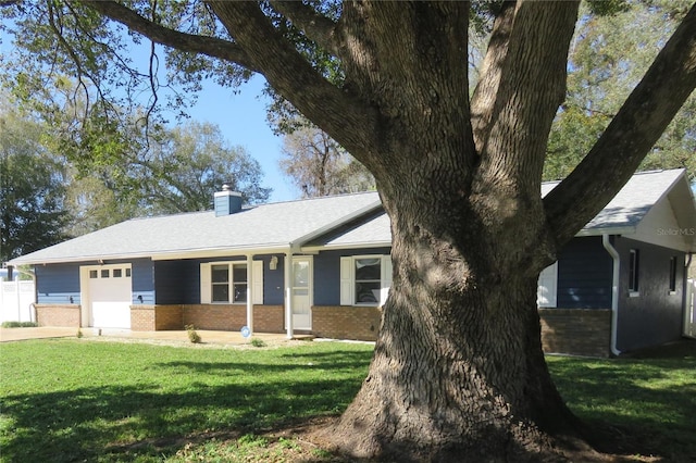 ranch-style house with a garage, brick siding, a chimney, and a front lawn