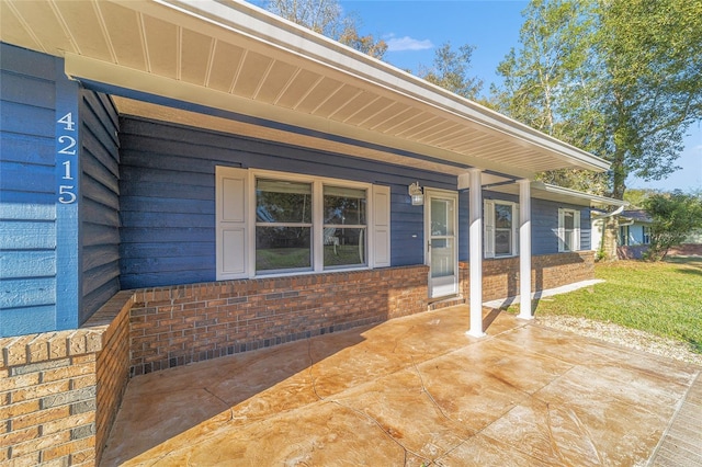 property entrance with a porch and brick siding