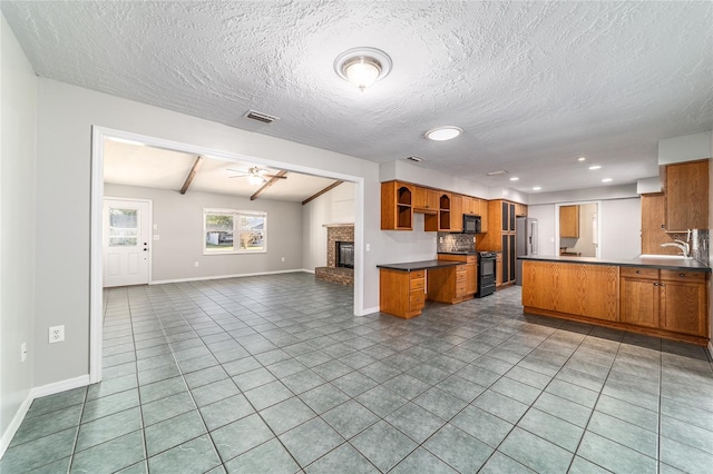 kitchen with visible vents, a ceiling fan, open floor plan, black appliances, and a fireplace