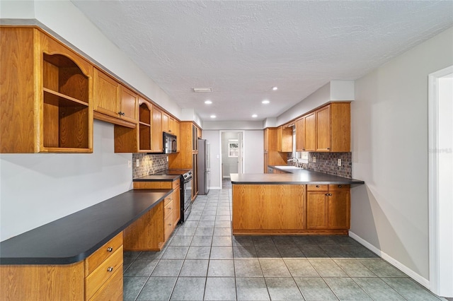 kitchen with a peninsula, a sink, brown cabinets, black appliances, and built in desk