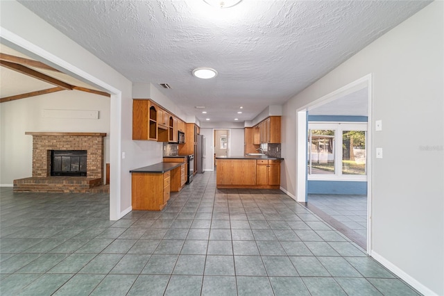 kitchen featuring brown cabinets, open shelves, dark countertops, open floor plan, and tile patterned flooring