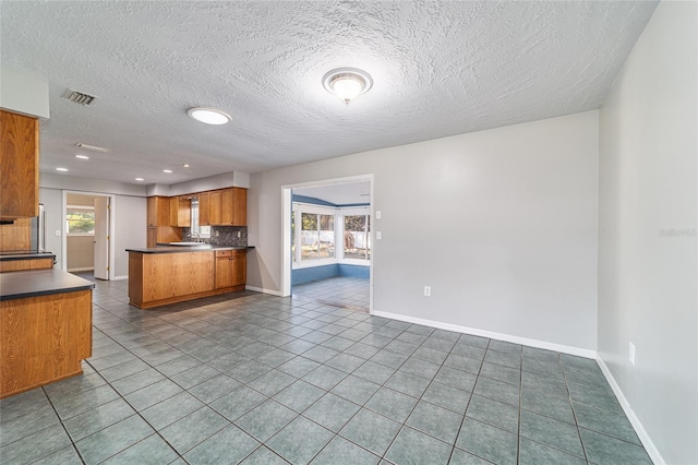 kitchen featuring dark countertops, open floor plan, a healthy amount of sunlight, and a peninsula