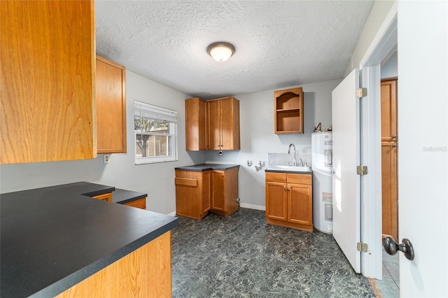 kitchen with a textured ceiling, electric water heater, a sink, open shelves, and brown cabinetry