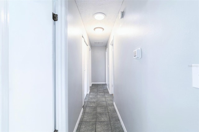 hallway featuring tile patterned flooring, baseboards, and a textured ceiling