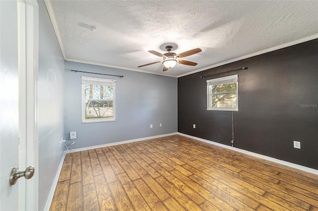 spare room featuring baseboards, a ceiling fan, ornamental molding, wood finished floors, and a textured ceiling