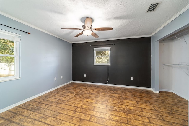 unfurnished bedroom with visible vents, crown molding, multiple windows, and wood finished floors