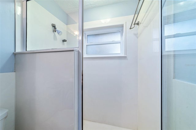 full bath with toilet, a textured ceiling, and a shower with door