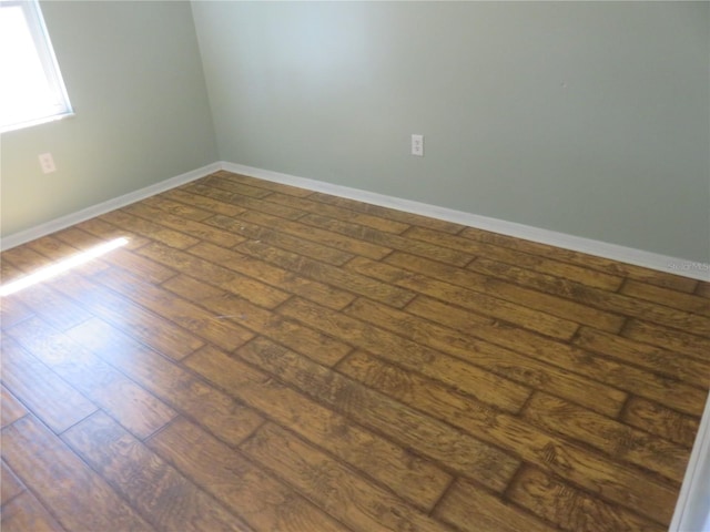 spare room featuring dark wood-style floors and baseboards