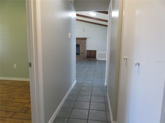 corridor with visible vents, lofted ceiling with beams, baseboards, and tile patterned floors