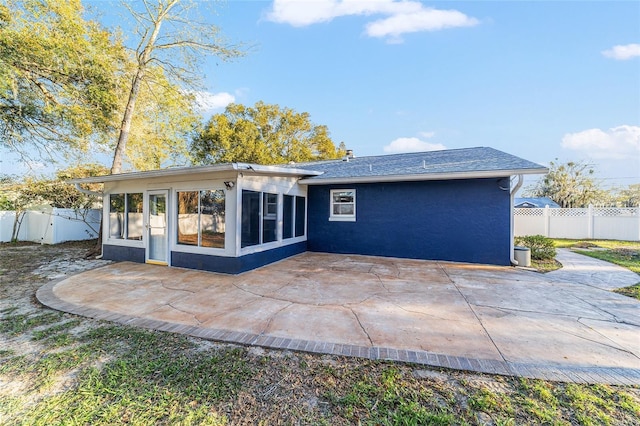 rear view of house featuring a sunroom, a patio, fence, and stucco siding