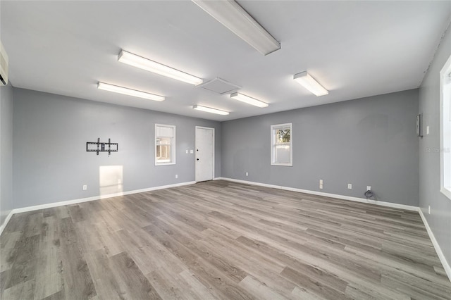 unfurnished room featuring attic access, baseboards, and wood finished floors