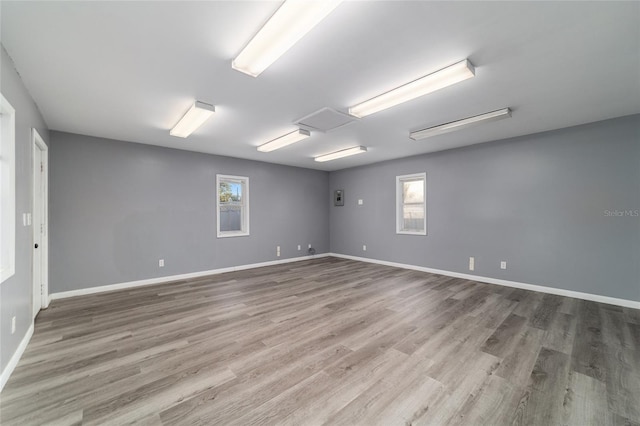 empty room featuring attic access, baseboards, and wood finished floors