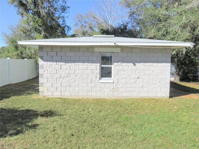 view of home's exterior featuring concrete block siding, a yard, and fence