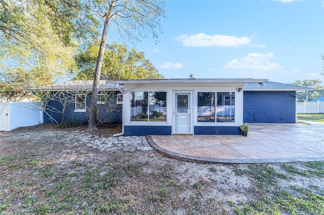 rear view of property featuring stucco siding, a patio, and fence