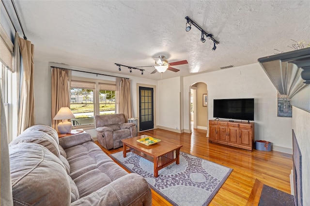 living room featuring ceiling fan, wood-type flooring, and a textured ceiling