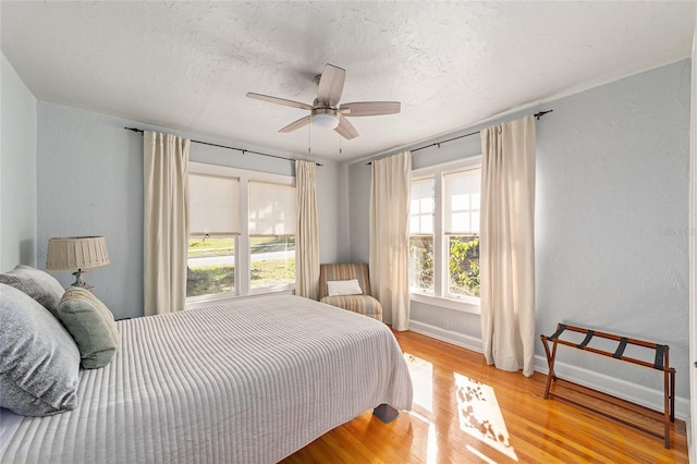 bedroom with ceiling fan, light hardwood / wood-style floors, and a textured ceiling