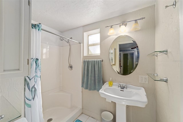 bathroom with sink, a shower with shower curtain, and a textured ceiling