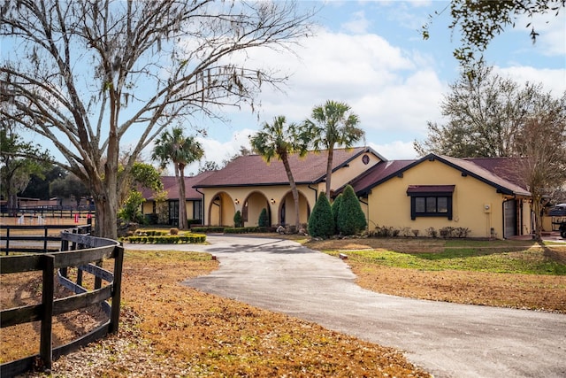 view of front facade featuring aphalt driveway, fence, a garage, and stucco siding