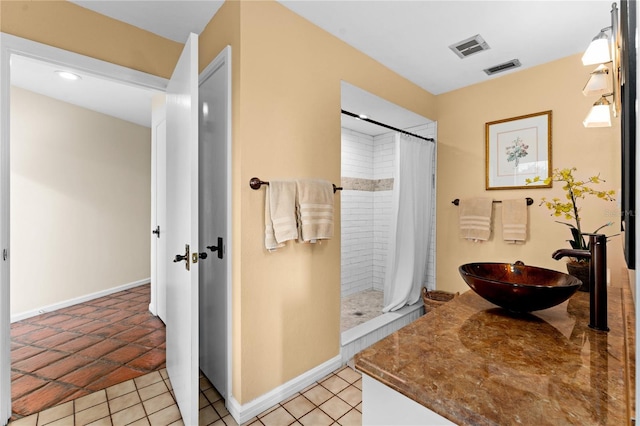 bathroom featuring visible vents, a sink, a shower stall, baseboards, and tile patterned floors