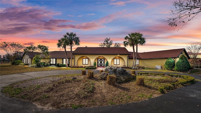 ranch-style home featuring curved driveway and stucco siding