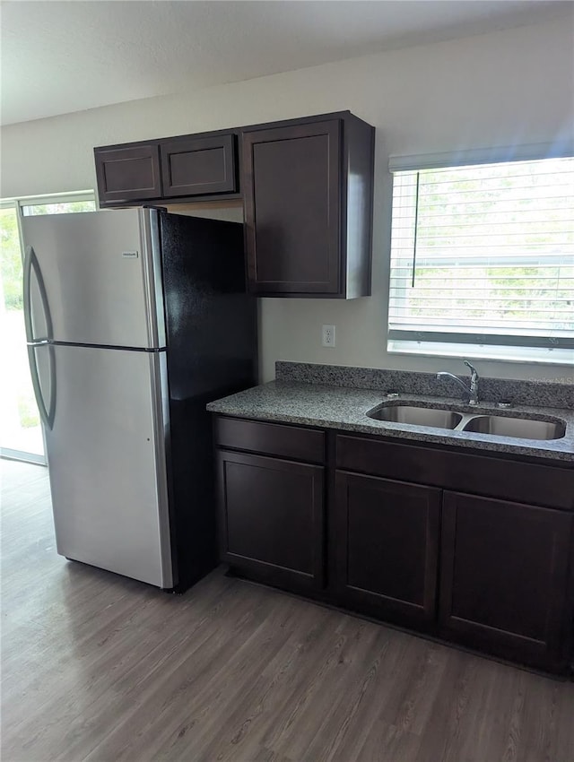 kitchen featuring hardwood / wood-style flooring, dark brown cabinets, sink, and stainless steel refrigerator