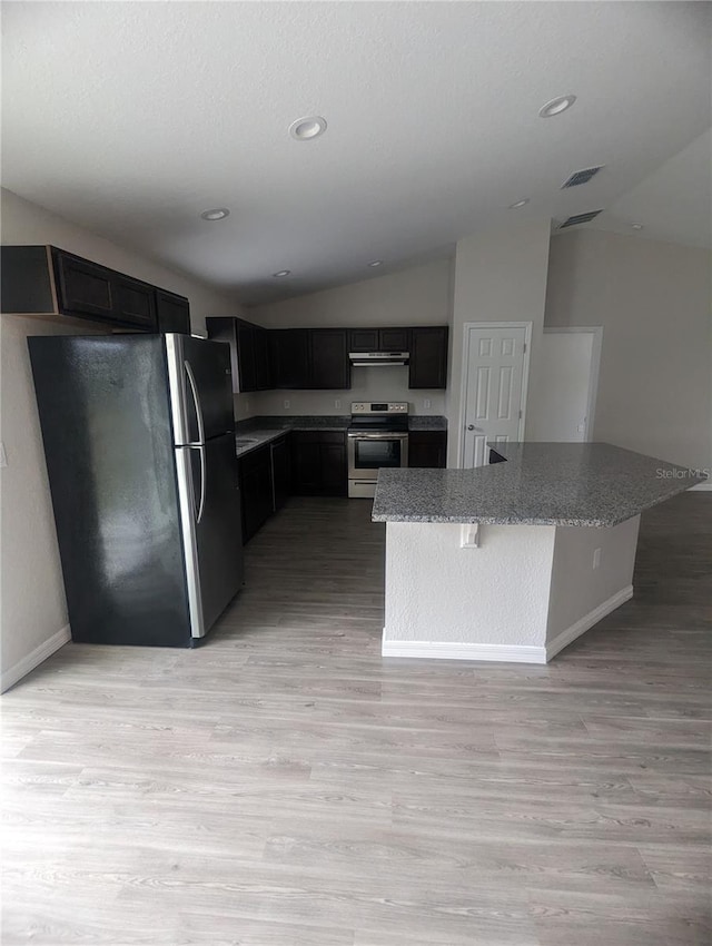 kitchen featuring lofted ceiling, light wood-type flooring, stone counters, and appliances with stainless steel finishes