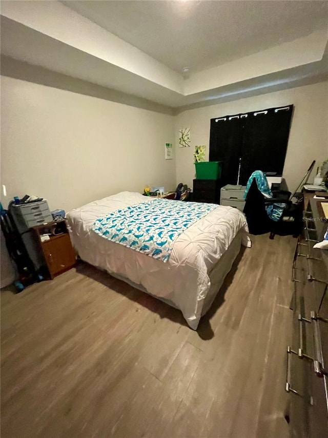 bedroom with hardwood / wood-style flooring and a raised ceiling