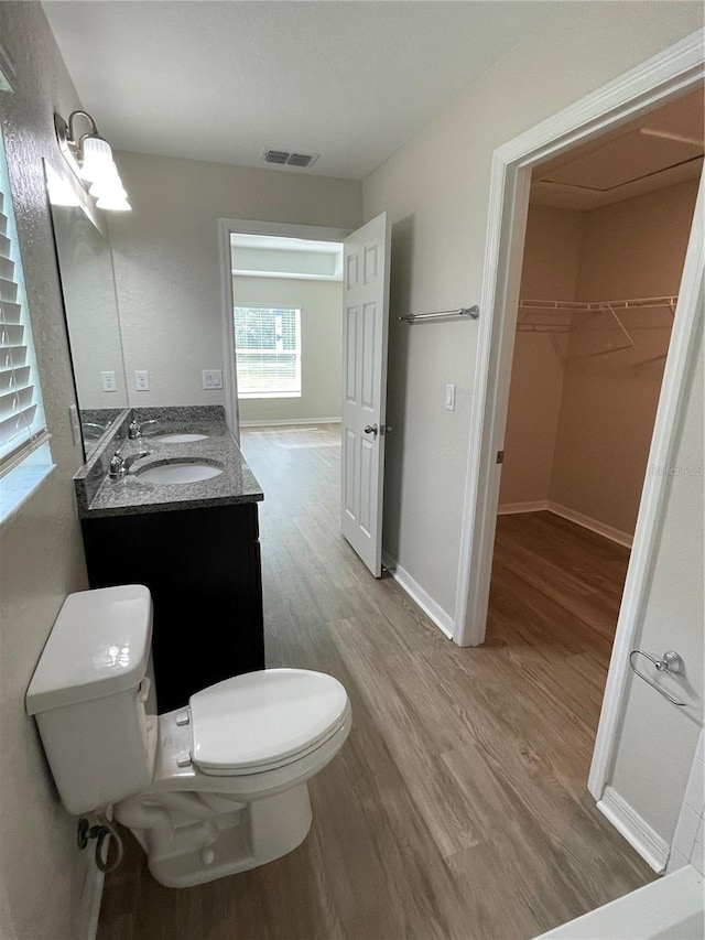 2792 SW 161st Loop, Ocala, FL 34473 - full bathroom with toilet, wood finished floors, double vanity, a spacious closet, and baseboards
