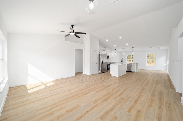 unfurnished living room featuring ceiling fan, sink, vaulted ceiling, and light wood-type flooring