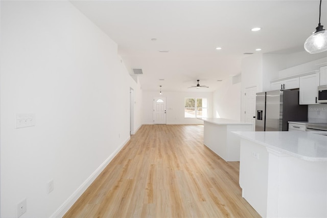 kitchen with appliances with stainless steel finishes, decorative light fixtures, white cabinets, ceiling fan, and light wood-type flooring