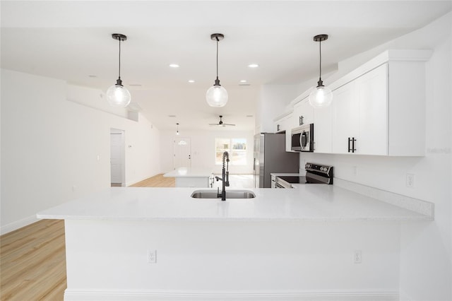 kitchen with stainless steel appliances, white cabinetry, sink, and kitchen peninsula