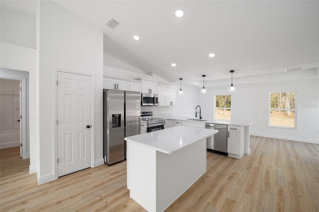 kitchen with sink, decorative light fixtures, kitchen peninsula, stainless steel appliances, and white cabinets