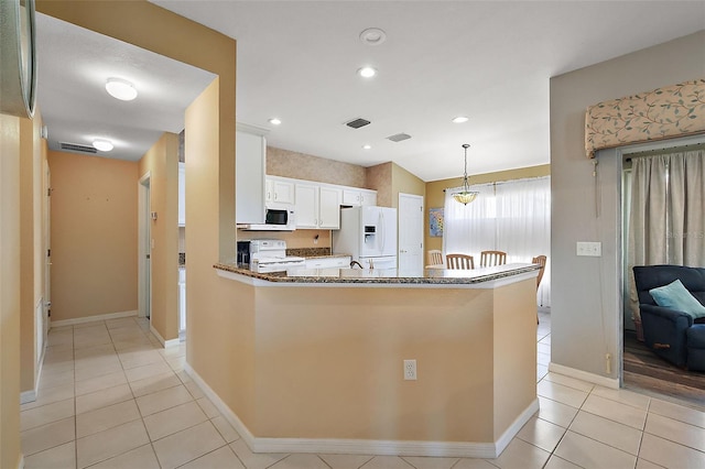 kitchen with light tile patterned floors, white appliances, white cabinetry, kitchen peninsula, and dark stone counters