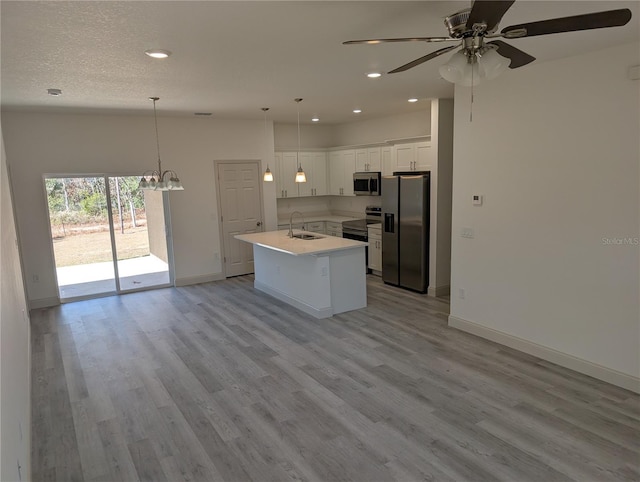 kitchen featuring sink, white cabinetry, decorative light fixtures, an island with sink, and stainless steel appliances