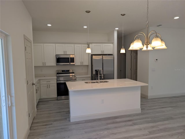 kitchen with appliances with stainless steel finishes, decorative light fixtures, an island with sink, and white cabinets