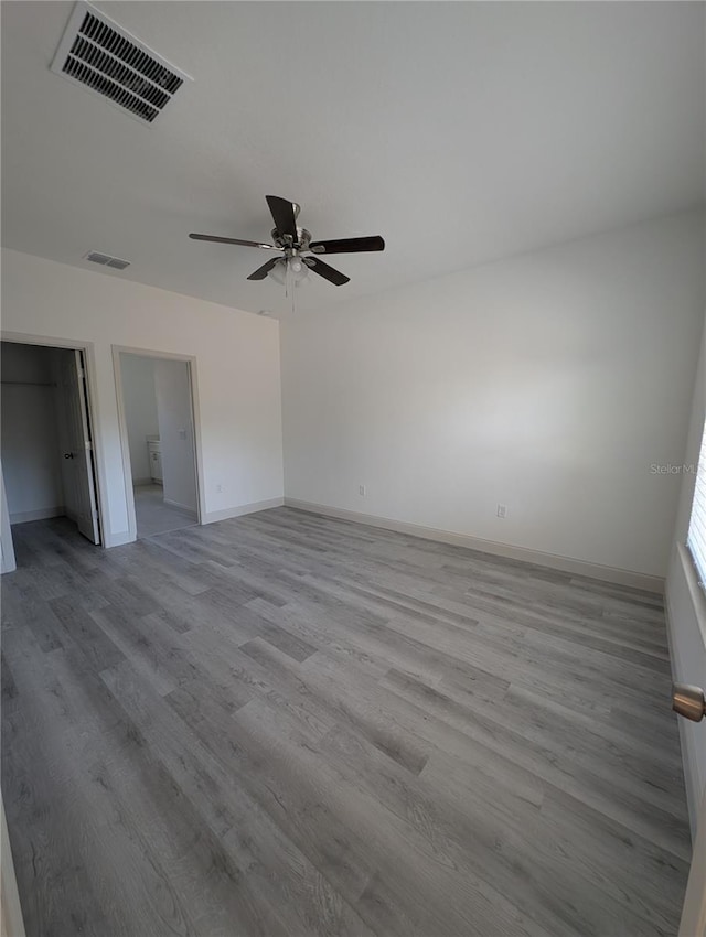 unfurnished bedroom with a walk in closet, light hardwood / wood-style floors, a closet, and ceiling fan