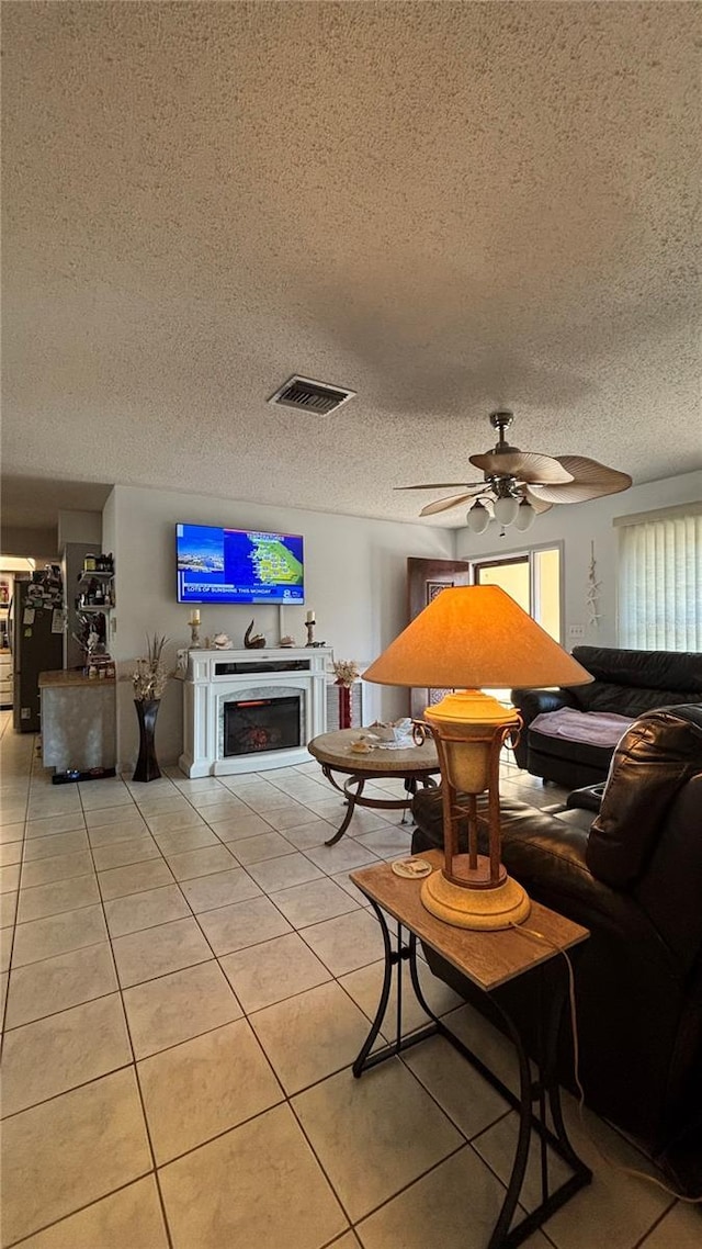 living room with light tile patterned flooring, ceiling fan, and a textured ceiling