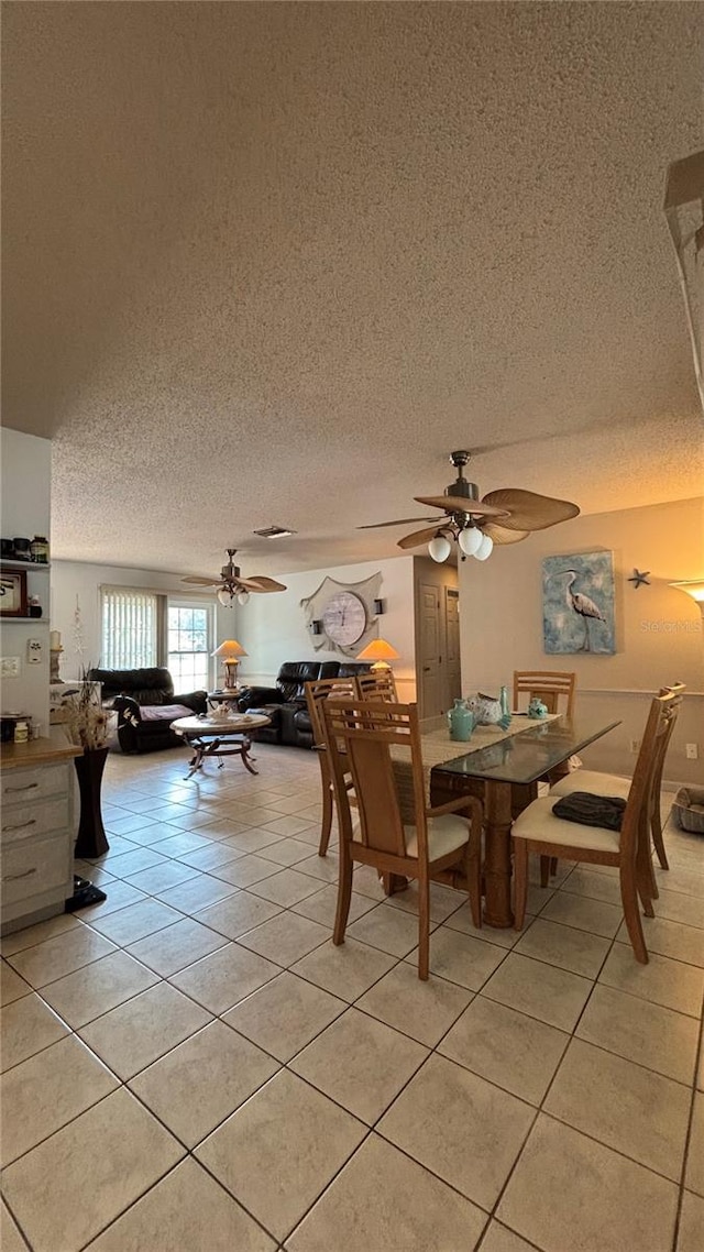 tiled dining space with a textured ceiling and ceiling fan