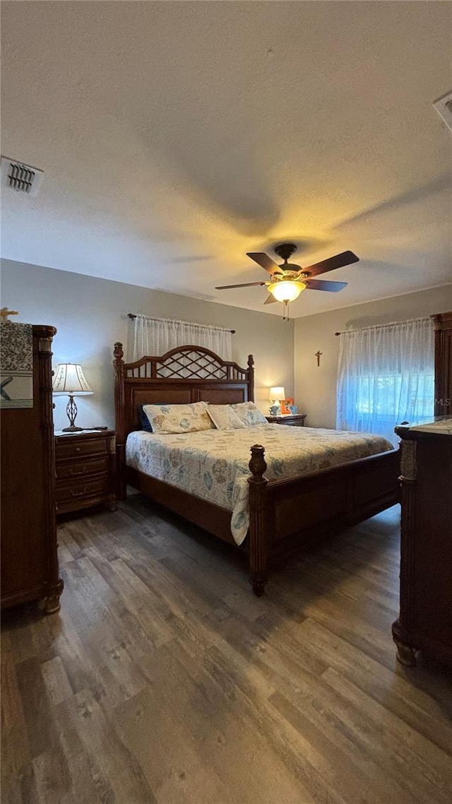 bedroom with dark hardwood / wood-style floors, a textured ceiling, and ceiling fan