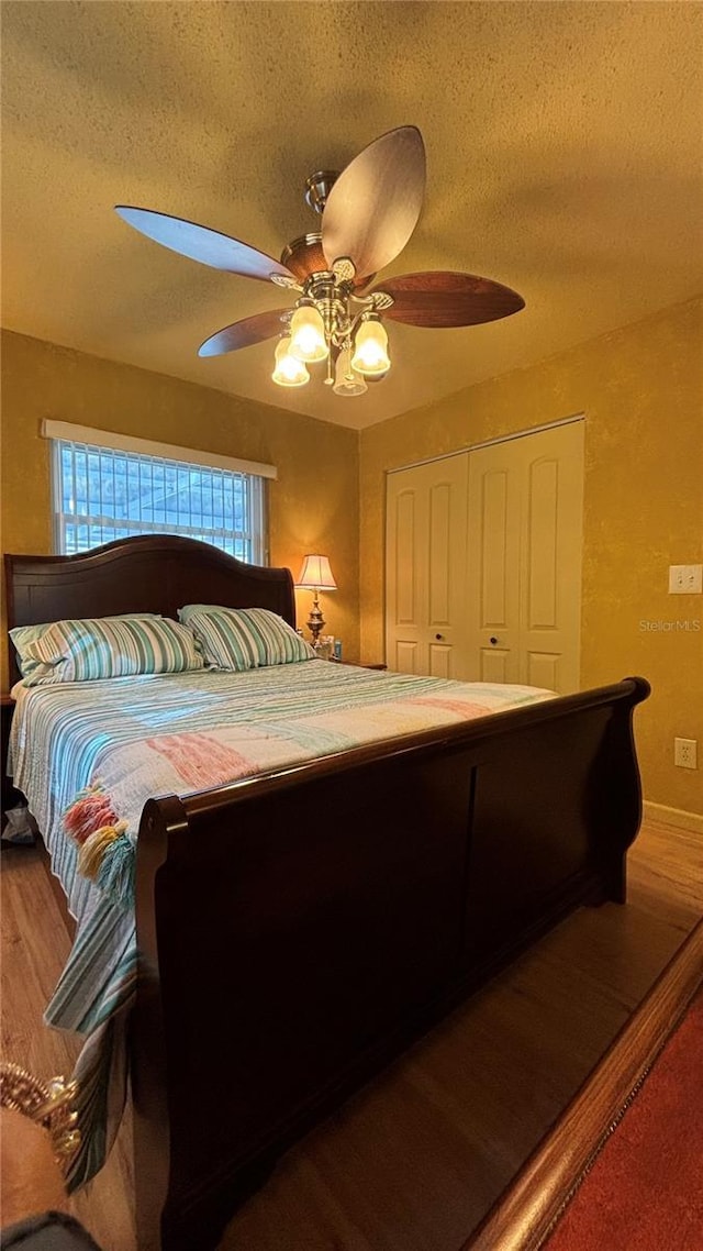 bedroom with a textured ceiling, wood-type flooring, a closet, and ceiling fan