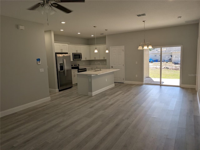 kitchen with appliances with stainless steel finishes, sink, white cabinets, hanging light fixtures, and a center island with sink